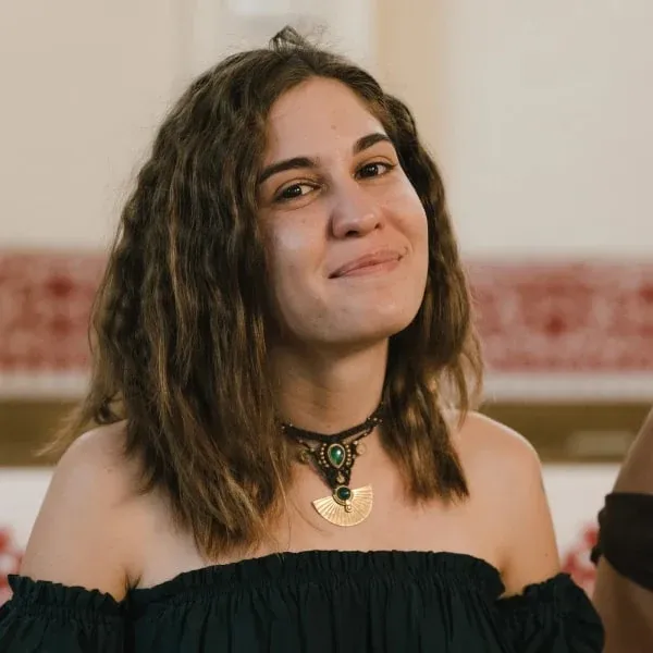 Meda Andreea Căpîlna, portret așezat la masă, în sacou verde-gri